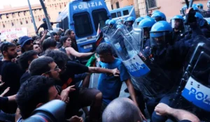 Schieramento delle forze dell'ordine e fumo durante gli scontri alla manifestazione a Bologna per la morte di Fakir Abderrahim.