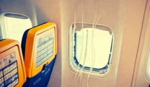 Dettaglio della fusoliera di un aereo con il telaio del finestrino danneggiato dopo l'incidente in quota.